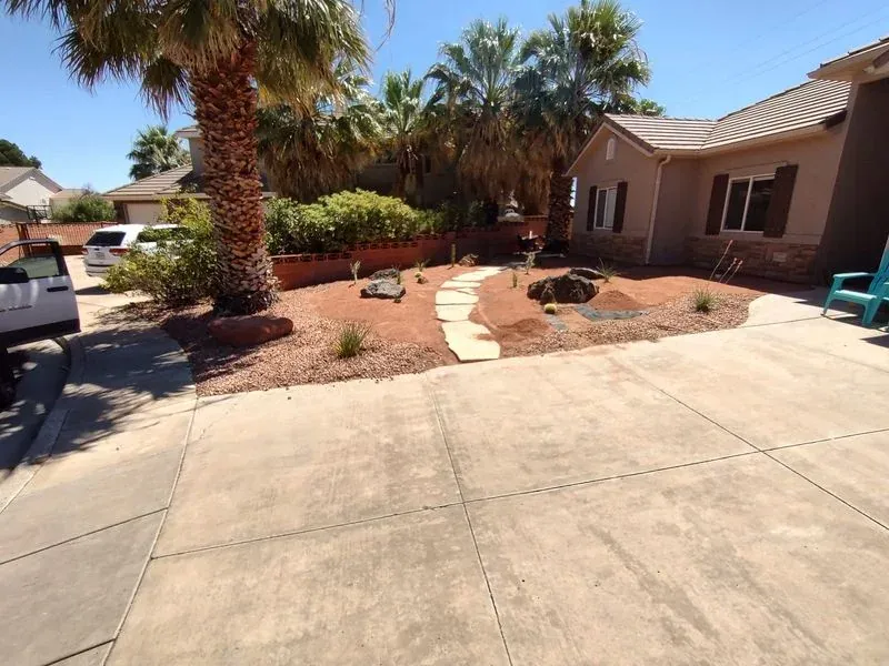 Desert landscape in Ivins Utah with flagstone stepping stone path, dry creek bed, boulders, agave and palms
