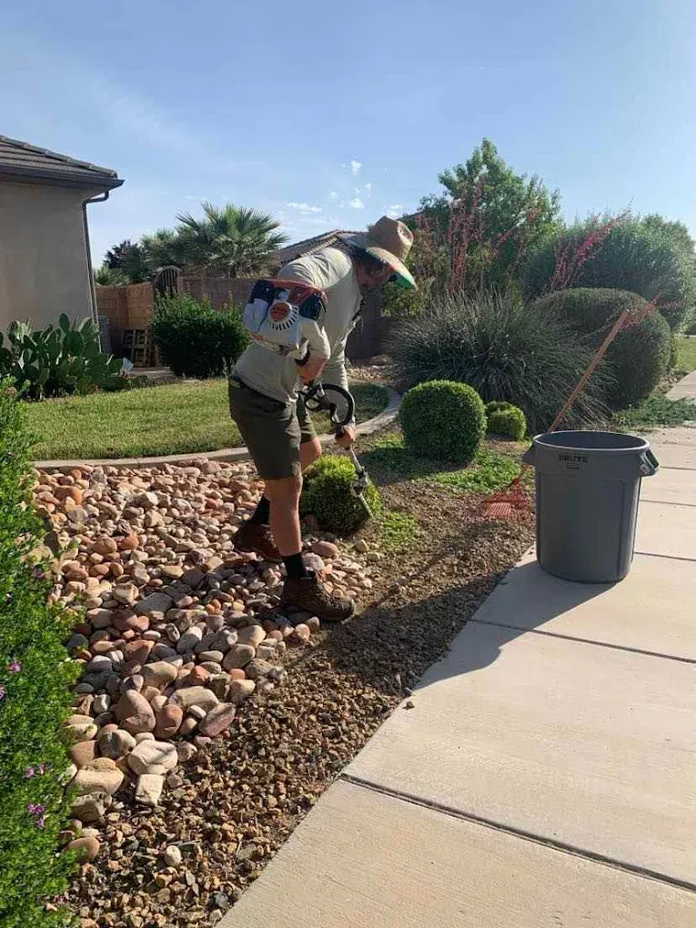 Precise Plants crew member edging a river rock bed alongside a sidewalk in Washington, Utah