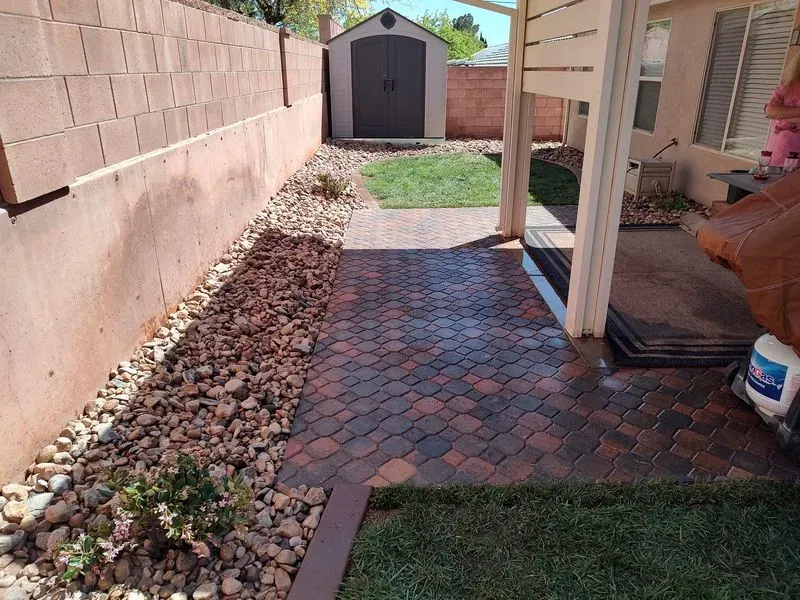 Multi-tone paver patio and walkway with river rock border in a Santa Clara Utah side yard
